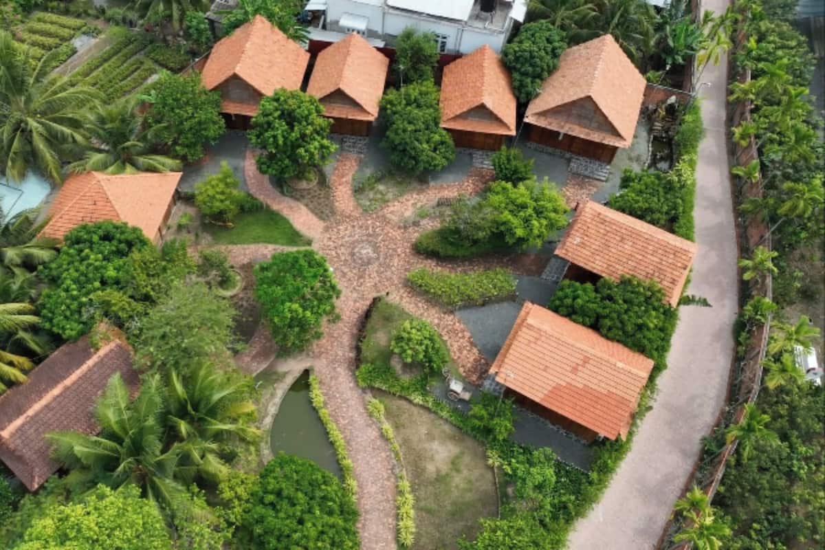 An aerial view of a resort with multiple bungalow-style buildings, surrounded by lush greenery and palm trees.