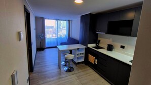 A compact kitchen with a dining area, a built-in TV, and a large window offering a view. - Your ideal place in the ideal sector of Santiago. 3rd floor (Ñuñoa)