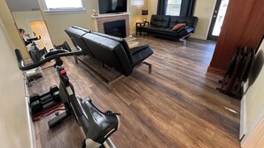 A living room with a stationary bike, a fireplace, a sofa, and a television.