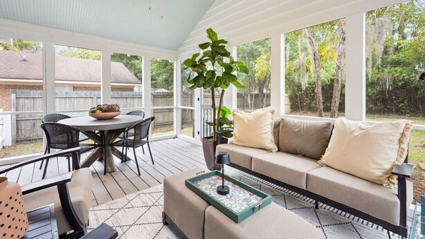 Une terrasse couverte avec une table ronde, des chaises, un canapé et une plante en pot.