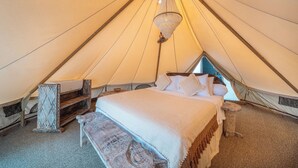A tent with a bed, a hanging light, and a small table. - Naluna Glamping Lembongan (Lembongan Island)