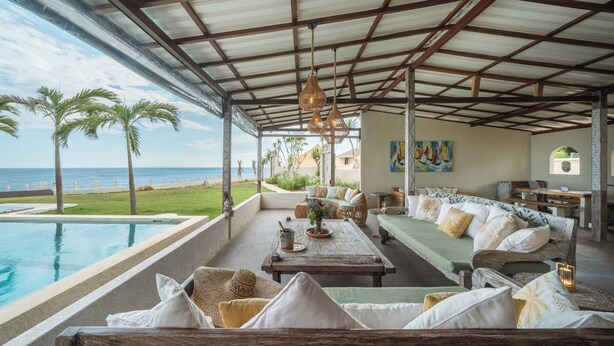 A covered outdoor seating area with a pool, palm trees, and a view of the ocean. - Naluna Glamping Lembongan (Lembongan Island)