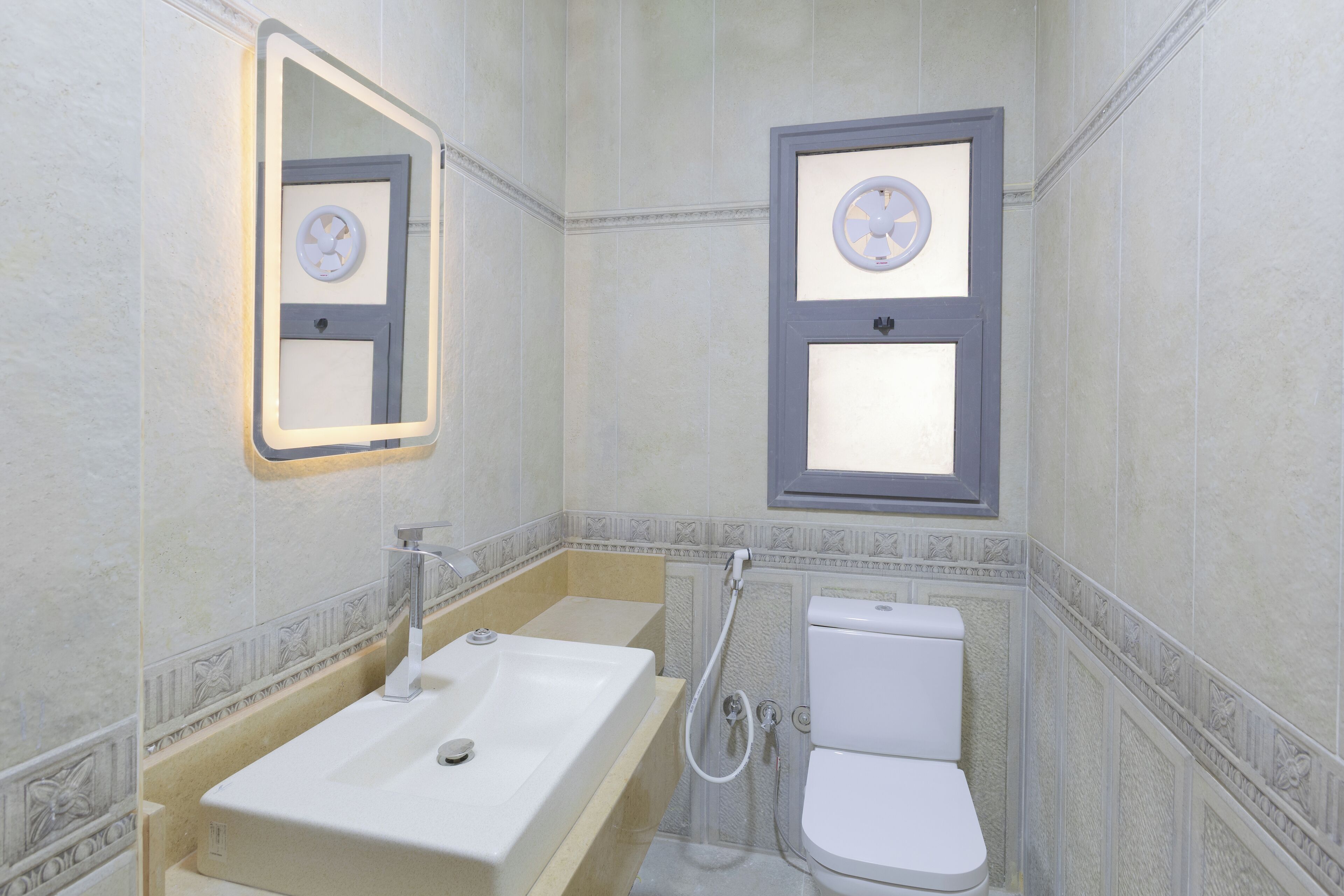 A bathroom with a large sink, a toilet, and a mirror.
