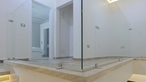 Un bagno moderno con cabina doccia in vetro, piano di lavoro in marmo e seduta integrata.