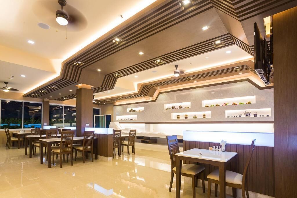 A modern restaurant with a sleek design, featuring a long counter, multiple seating areas, and a polished floor.