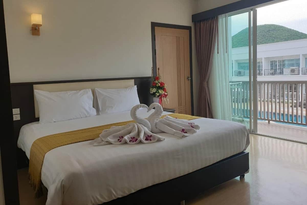 Une chambre d’hôtel avec un grand lit, une vue sur la piscine et une porte donnant sur le balcon.