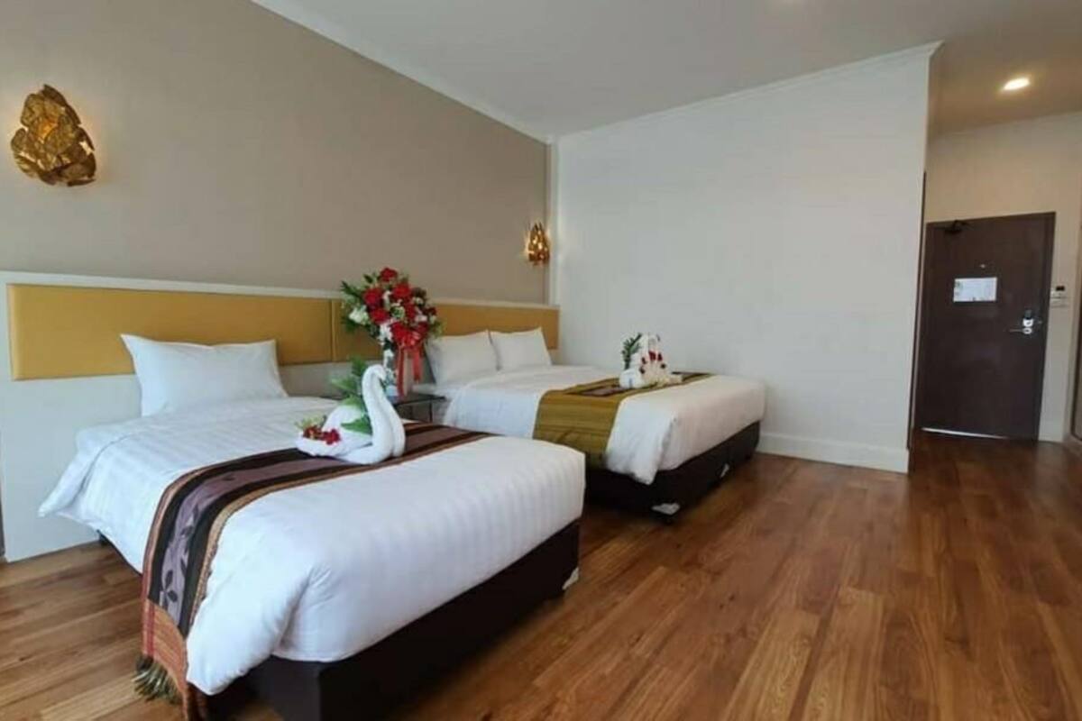 Une chambre d’hôtel avec deux lits, un plancher en bois, un élément décoratif mural et une porte.
