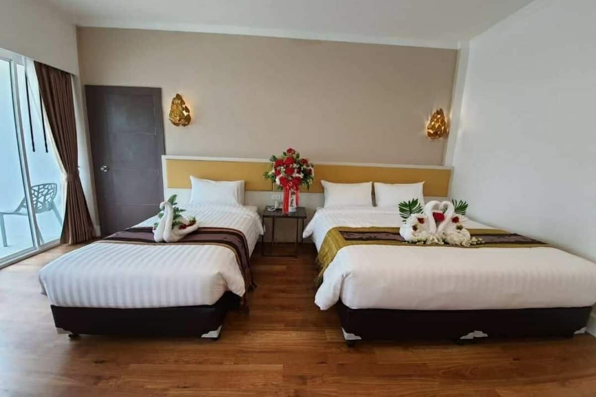 Une chambre d’hôtel avec deux lits, une table de chevet et une grande fenêtre.