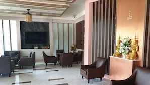 A modern lobby with a large TV screen, comfortable seating, a patterned floor, and decorative elements. - Swan Lake Hotel Sattahip (Sattahip)
