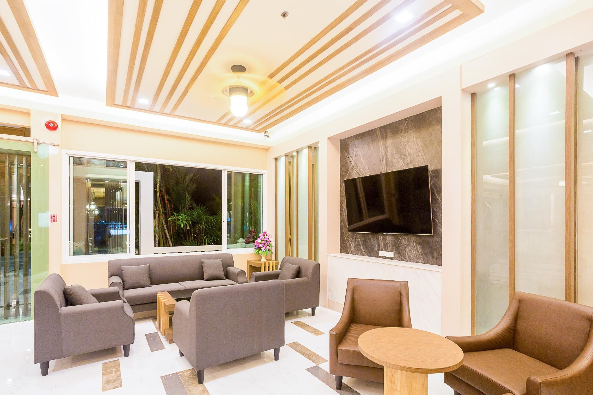A modern lobby with sofas, a round table, and a large TV screen.