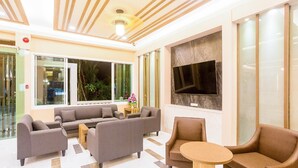 Eine moderne Lobby mit Sofas, einem runden Tisch und einem großen Fernsehbildschirm.