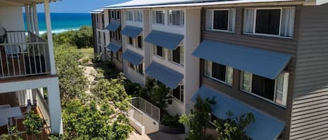 Un hôtel à plusieurs étages doté de balcons donnant sur une plage.
