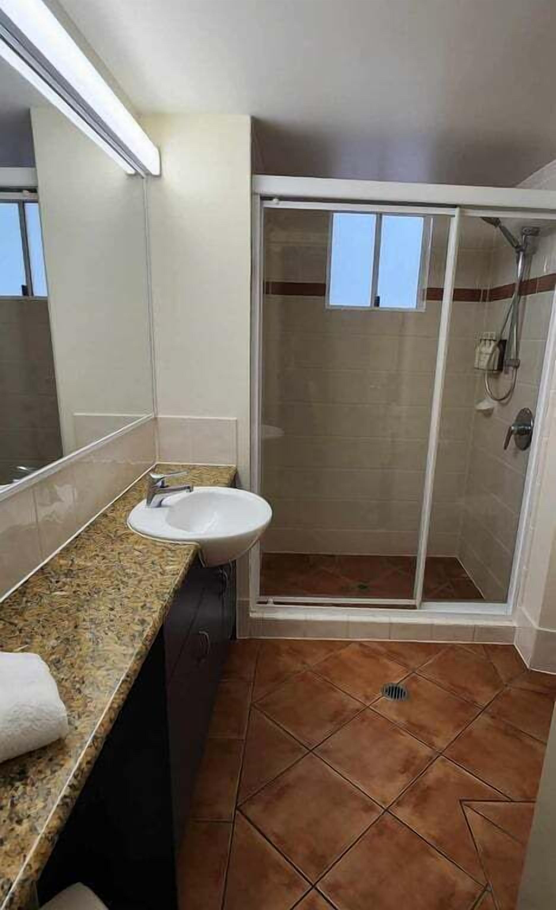 A bathroom with a sink, a shower, and a tiled floor.