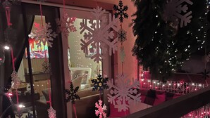 Un balcón con barandilla adornado con luces y adornos con forma de copo de nieve.