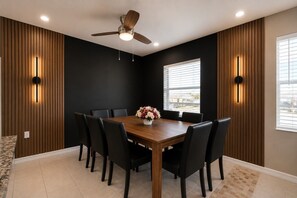 A dining room with a wooden table, black chairs, a ceiling fan, and wall-mounted lights. - 4BR 2BA Pool Hot Tub BBQ Mini Golf Sleep 12 (Port Charlotte)
