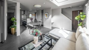 A modern living room with a sofa, coffee table, and potted plants. - THE SHIMMER FURANO (Furano)