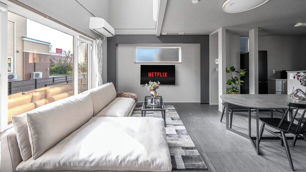 A modern living room with a sofa, coffee table, and dining area. - THE SHIMMER FURANO (Furano)