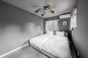 Et moderne hotelværelse med en stor seng, en lampe i loftet og et vindue med gardiner.
