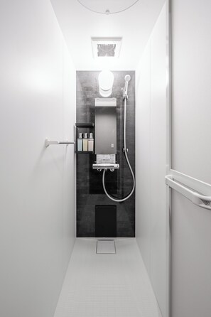 Et moderne bruseområde med glasvæg, håndbruser og kontrolpanel på væggen.