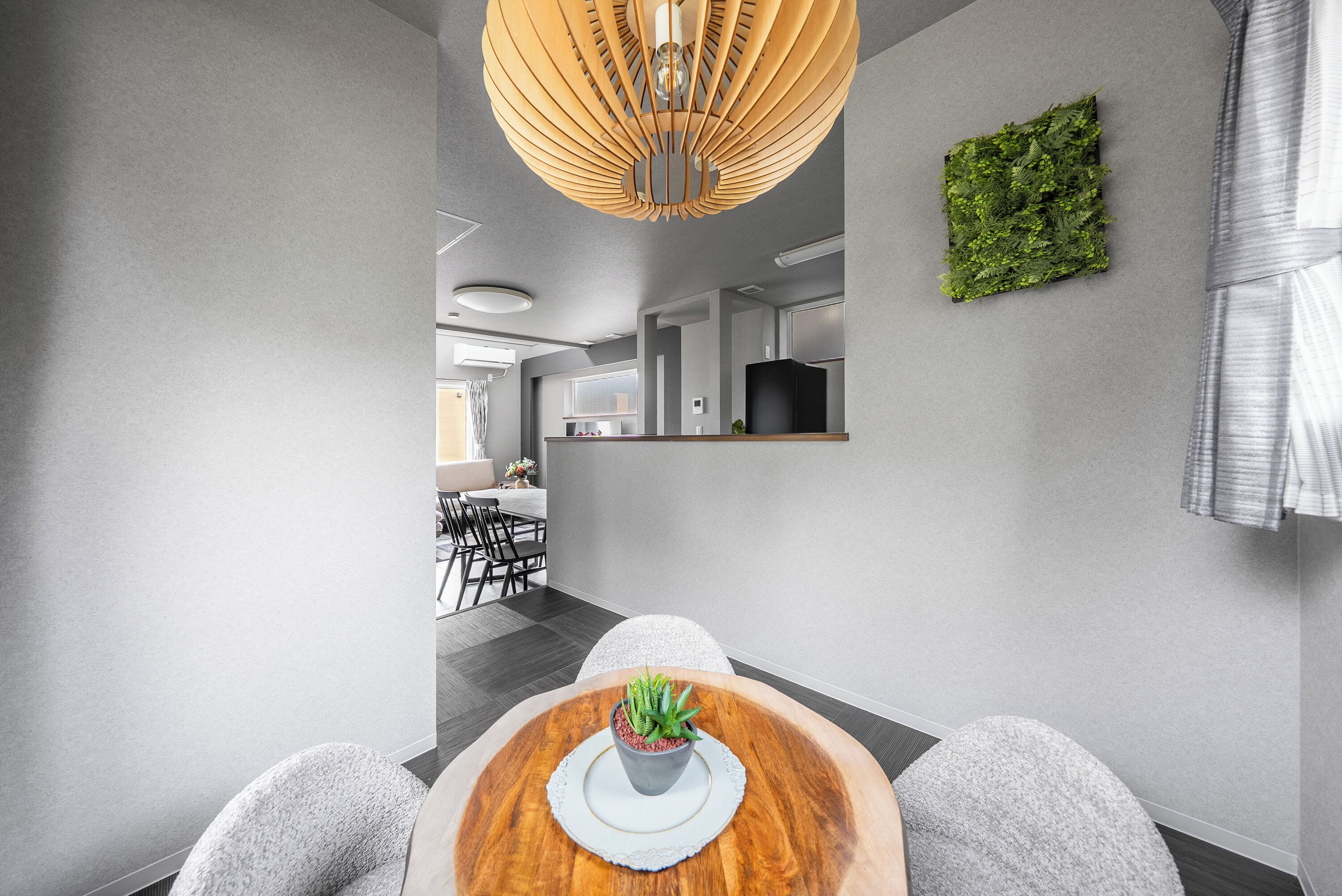 A modern dining area with a round wooden table, grey upholstered chairs, and a potted plant.