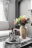 Una mesa con un jarrón de flores, dos vasos de vidrio y una bandeja decorativa.