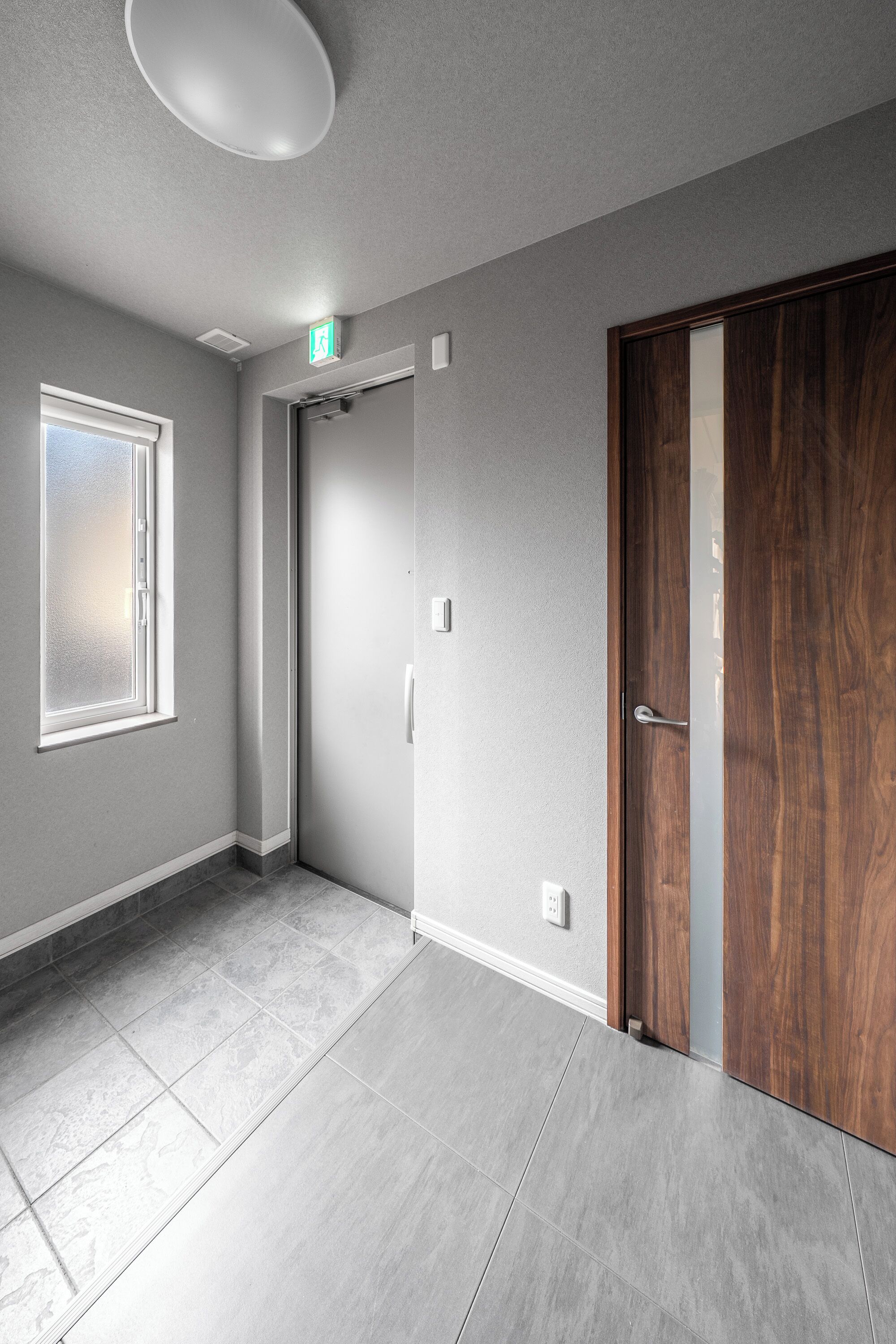 Una habitación con un ventanal grande, una puerta y un interruptor de luz en la pared.