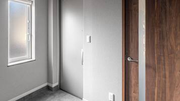 Una habitación con un ventanal grande, una puerta y un interruptor de luz en la pared.