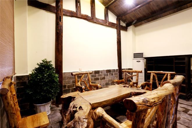 Un'area pranzo rustica con tavolo e panche in legno, una pianta in vaso e un muro in mattoni.