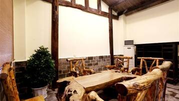 Un'area pranzo rustica con tavolo e panche in legno, una pianta in vaso e un muro in mattoni.