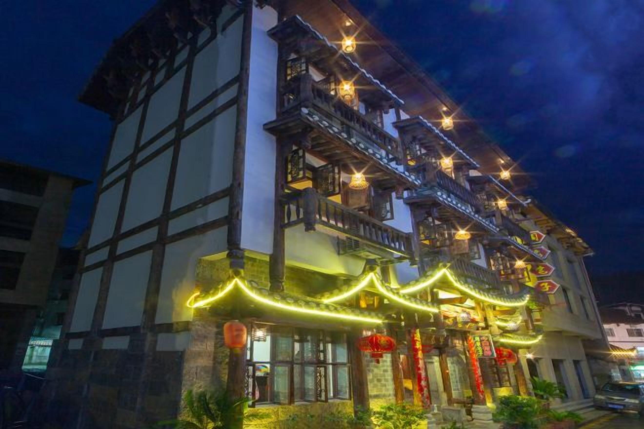 A traditional building with multiple floors, balconies, and a lit entrance.