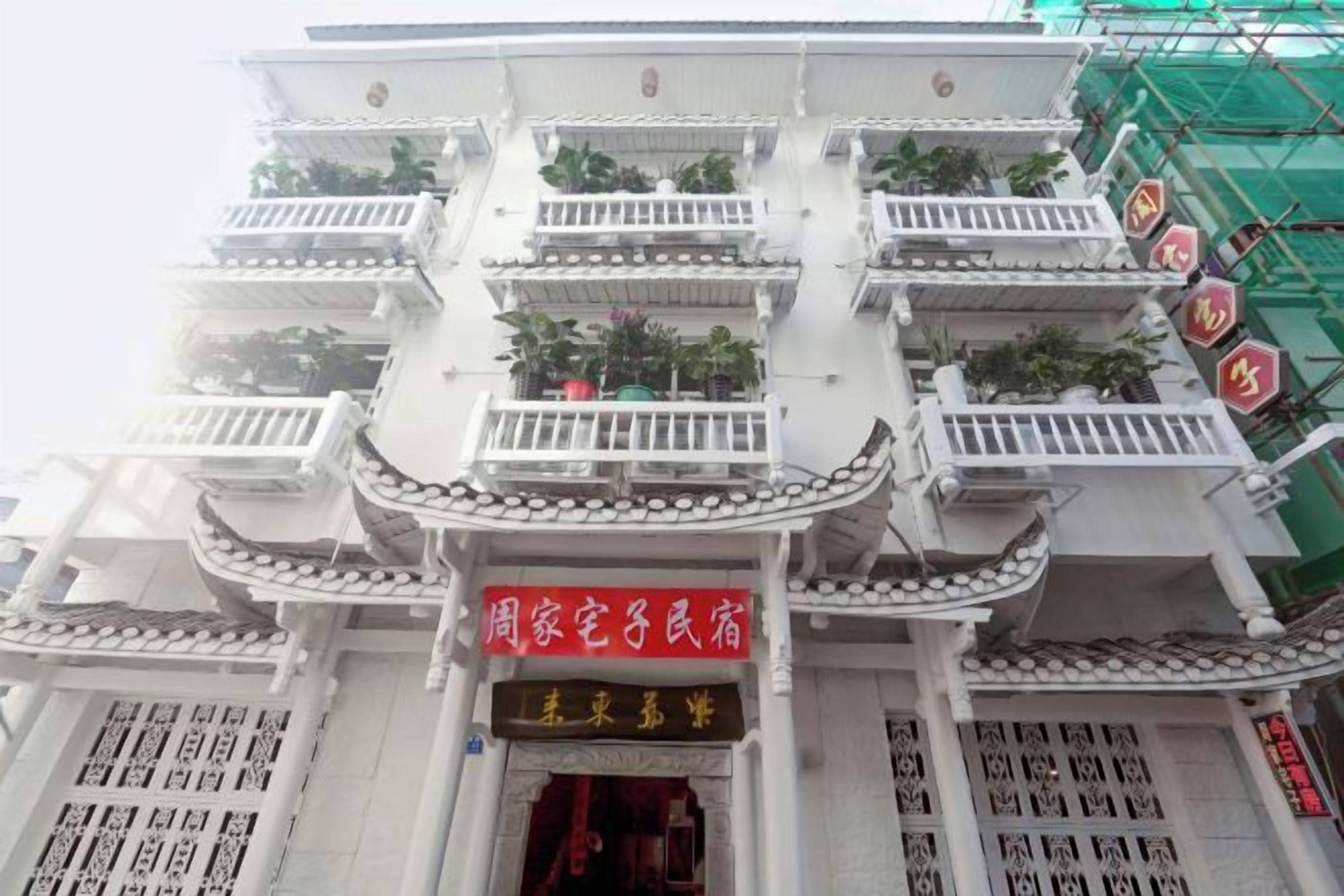 A multi-story building with balconies and a red sign indicating a residential area.