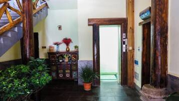 Een hal met een houten trap, een decor kast met planten, en een deur naar een andere kamer.