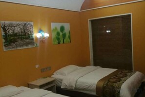 A hotel room with two beds, a nightstand, a wall-mounted lamp, and a window with a blind. - Zhoujia Zhaizi (Zhangjiajie National Forest Park) (Zhangjiajie)