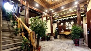 Una escalera de madera con plantas en macetas, suelo de piedra y decoración de estilo asiático tradicional.