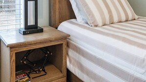 A bedroom with a wooden headboard, a bedside table with a lamp, a striped bedspread, and a map on the wall. - Spacious, Pristine Home w/ Firepit, Bourbon Lounge (Bardstown)