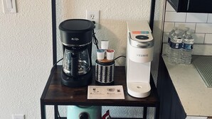 A kitchen counter with a coffee maker, a kettle, and a water dispenser.