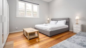 Een slaapkamer met een bed, nachtkastjes, een raam en een houten vloer.