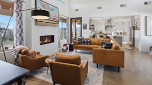 Uma sala de estar ampla com lareira, móveis modernos e vista para a cozinha.