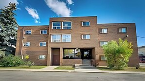 A two-story brick building with a central entrance, multiple windows, and a small tree in front. - Chinook II.
Pet Friendly 
 Nutrien ,CGC Inc Wheatland Plant, De Havilland. (Strathmore)