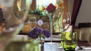 A dining table with a vase of flowers, a glass of water, and a wine glass.