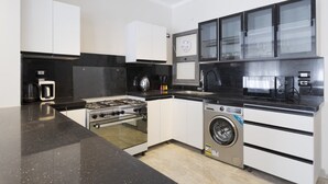 A compact kitchen with a gas stove, oven, washing machine, and a microwave. - Al-Sawah  Upper Duplex 3BR – Eastown Sodic (New Cairo)