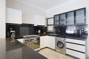 Eine kompakte Küche mit Gasherd, Backofen, Waschmaschine und Mikrowelle.