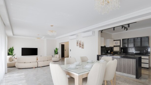 A modern living room with a glass dining table, white sofas, and a flat-screen TV. - Al-Sawah  Upper Duplex 3BR – Eastown Sodic (New Cairo)