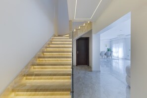 Eine moderne Treppe mit Glastrennwand und einer dunklen Tür am oberen Ende.
