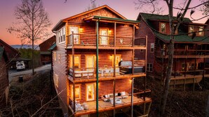 Ein mehrstöckiges Blockhaus mit Balkonen, Sitzgelegenheiten im Freien und einer sichtbaren Garage.