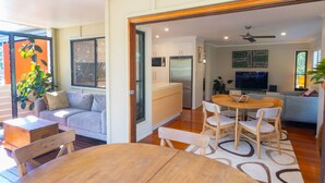 A modern kitchen with a built-in fridge, wooden cabinets, and a dining area with a round table and chairs. - Melaleuca Lookout - Modern 3-Bedroom Townhouse with Ocean Wiews (Point Lookout)