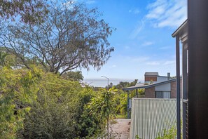 A residential property with a view of the ocean, a covered outdoor area, and a variety of vegetation.