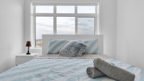 A bedroom with a bed, a window, and a nightstand. - Modern 3BR Townhome in Seton with Garage + Balcony (Calgary)