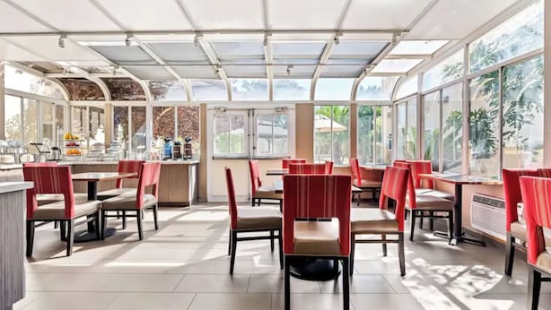 Un restaurante espacioso con techos altos y ventanas amplias que dejan entrar abundante luz natural.