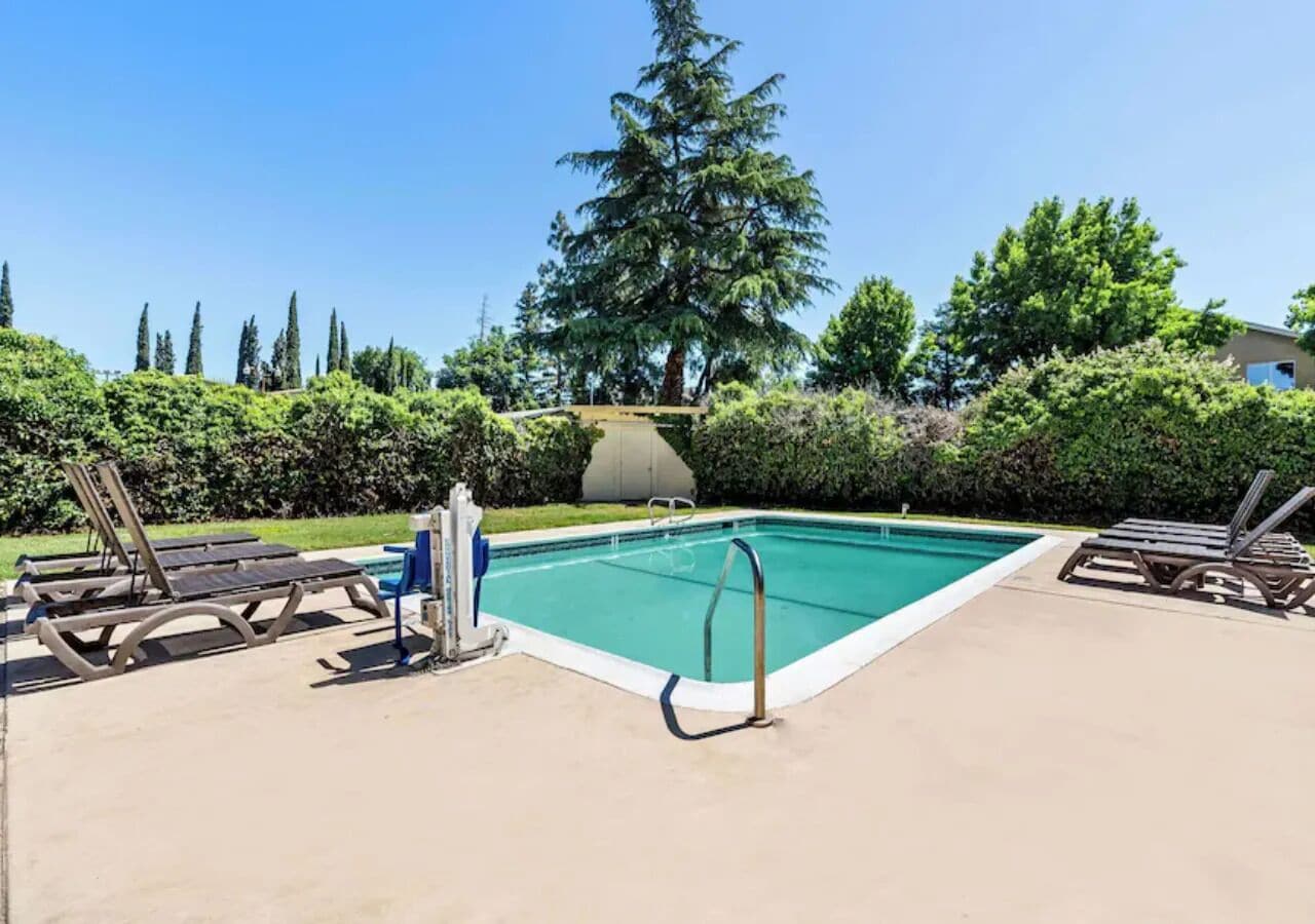 A rectangular swimming pool with a metal ladder and a small deck area.